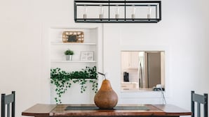 A dining area with a wooden table, black benches, a woven vase, and a pendant light fixture. - The Kennewick Cottage  (Kennewick)