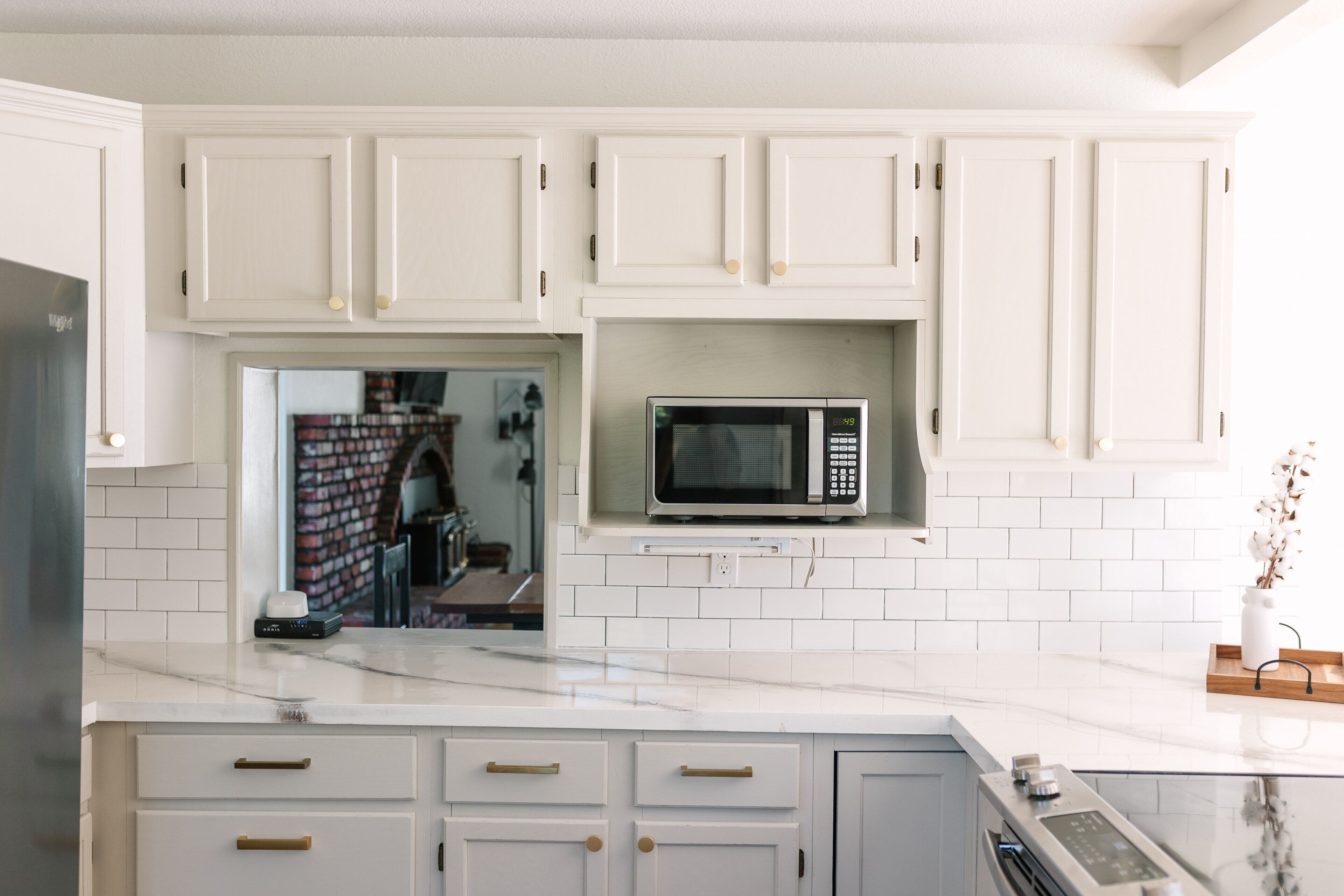 A kitchen with white cabinets, a microwave, and a built-in oven.