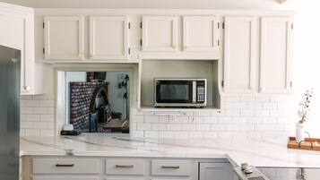 A kitchen with white cabinets, a microwave, and a built-in oven.