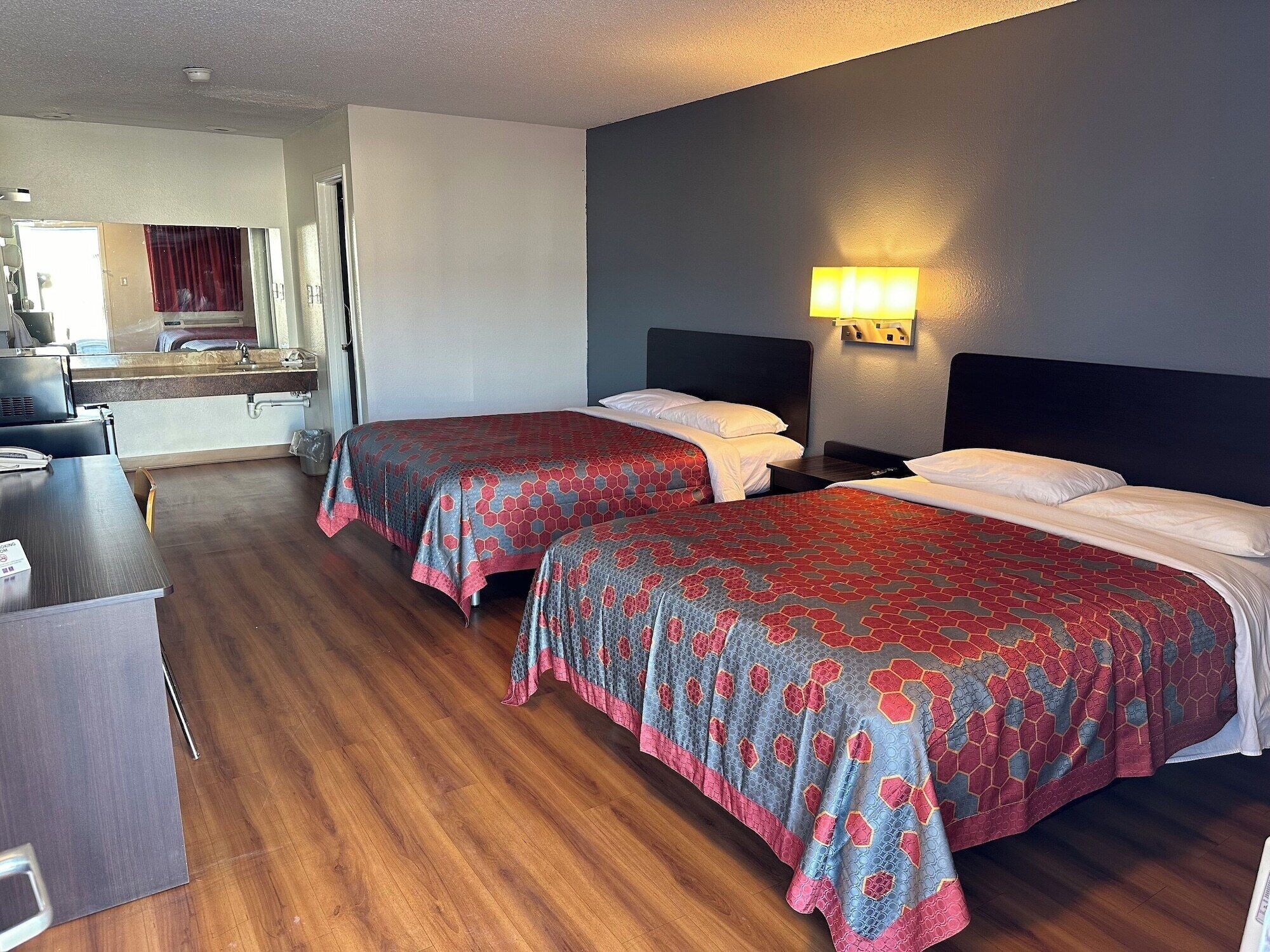 Ett hotellrum med två sängar, ett skrivbord och ett badrum som syns genom en öppen dörr.
