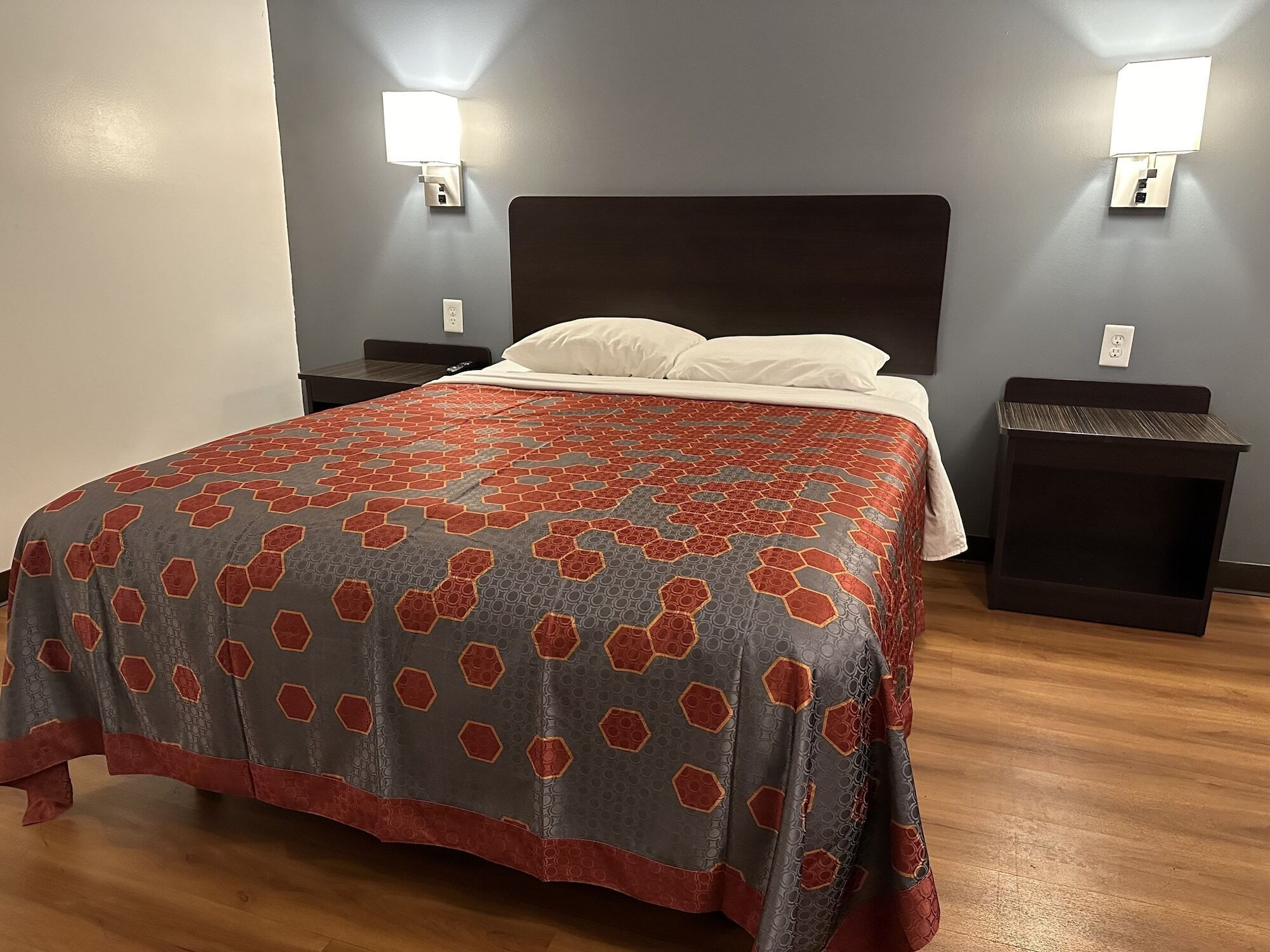 A hotel room with a large bed, two bedside tables, and two wall-mounted lights.