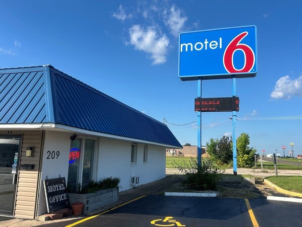 A motel with a blue roof, a digital signboard, and a handicap parking space.