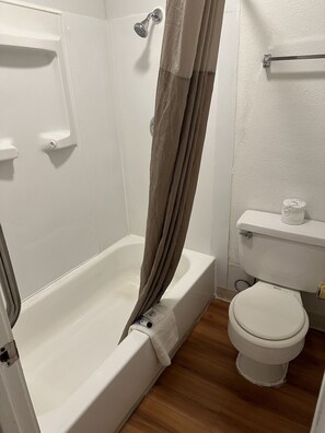 A bathroom with a bathtub, toilet, and shower curtain.