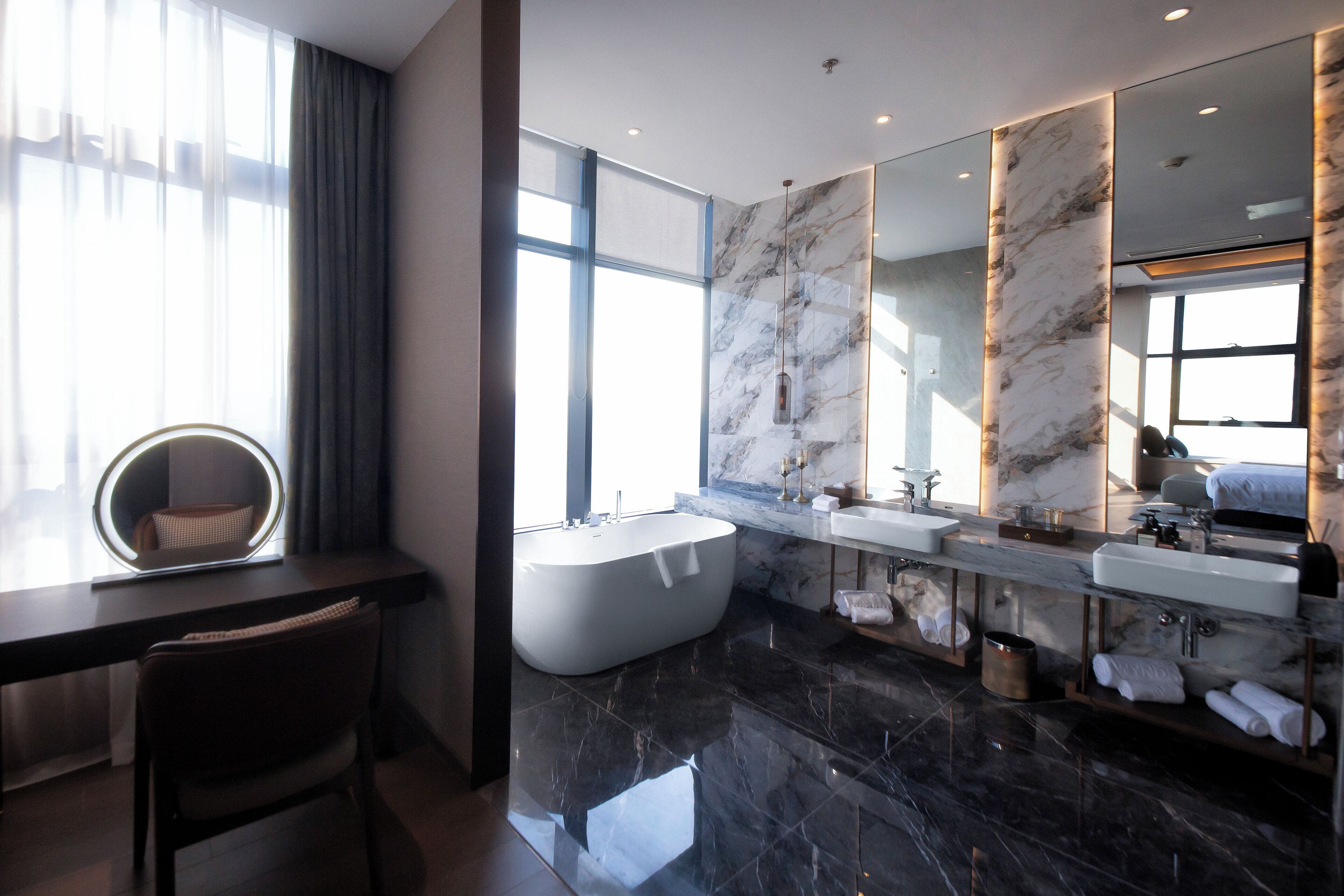 Un bagno moderno con una vasca da bagno ampia, due lavandini e un mobile vanitario con specchi.