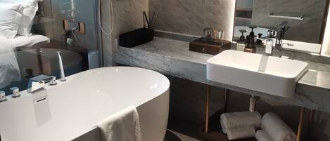 A modern bathroom with a large bathtub, a vanity with a mirror, and a towel rack.