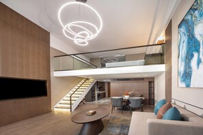 A modern interior with a staircase leading to an upper level, a dining area with a table and chairs, and a large abstract painting on the wall. - Wyndham Dalian Jinpu (Dalian)