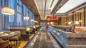 Eine moderne Hotelhalle mit einer langen Rezeption, einer Sitzecke und einer dekorativen Statue.
