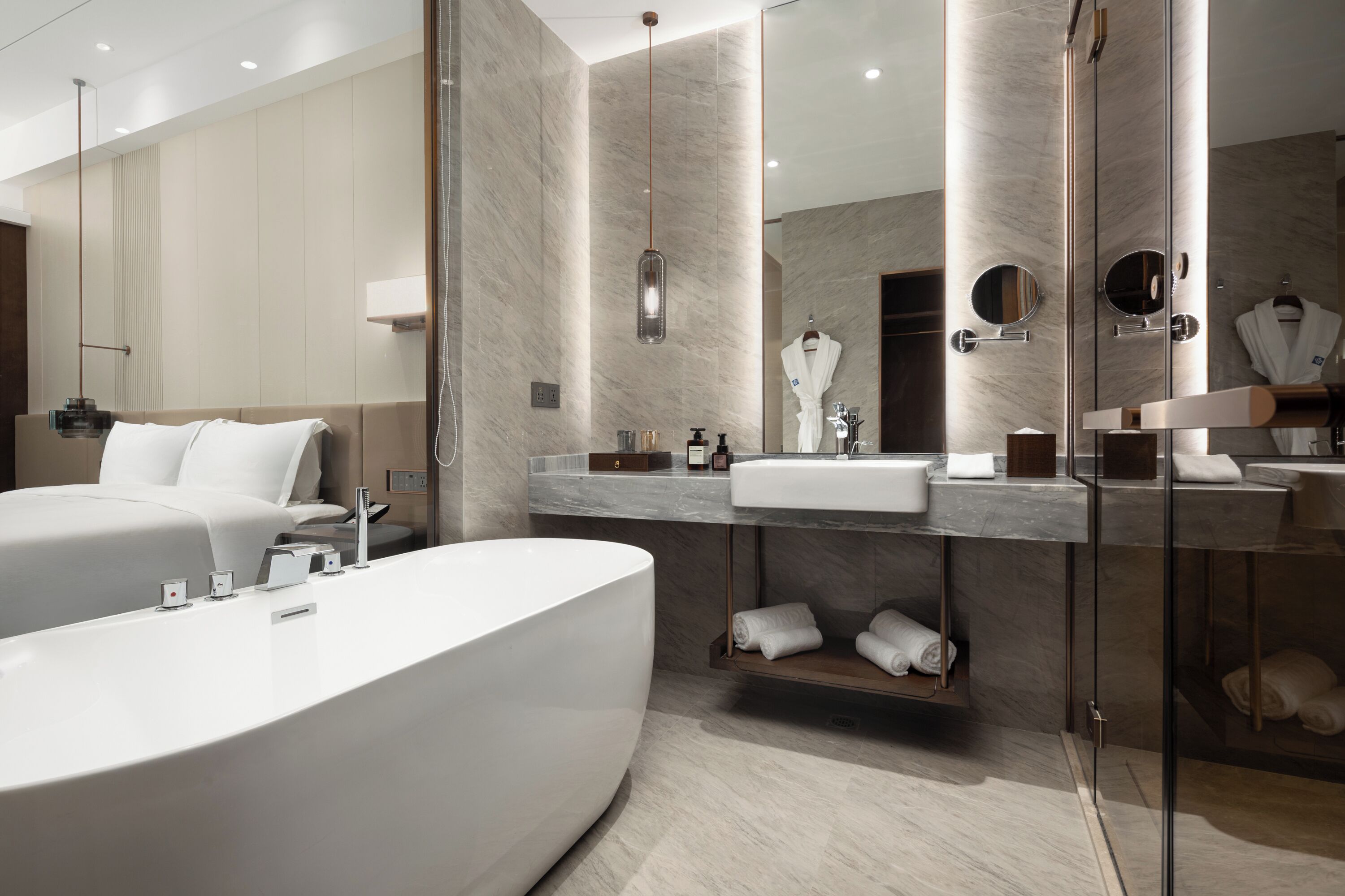 A modern bathroom with a large bathtub, a vanity with a mirror, and a robe hanging on a rack.