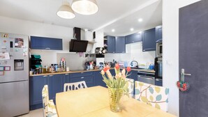 Une cuisine moderne avec des meubles de rangement bleus, une table à manger en bois et un vase rempli de fleurs.