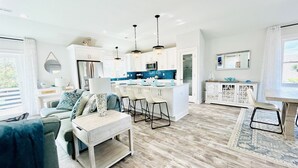 Une cuisine moderne avec des meubles blancs, un îlot central et des luminaires suspendus.