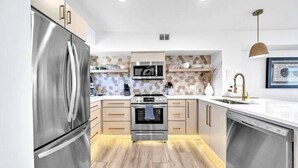 Eine moderne Küche mit Edelstahlgeräten, Holzschränken und einer dekorativen Spritzschutzwand.