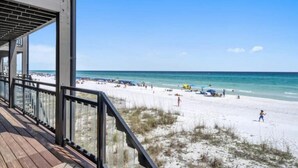 A beach view from a wooden deck with a railing, overlooking a sandy beach with people and beach umbrellas. - Gulf Front Luxury-Ocean View Suites! Private Beach (Destin)