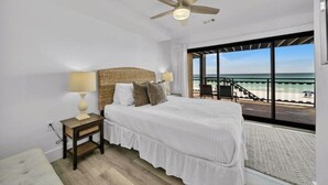 A bedroom with a large bed, a ceiling fan, a nightstand, and a view of the beach through large windows. - Gulf Front Luxury-Ocean View Suites! Private Beach (Destin)