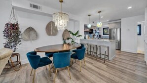 Une cuisine moderne dotée d’un îlot central, de tabourets de bar et de luminaires suspendus.