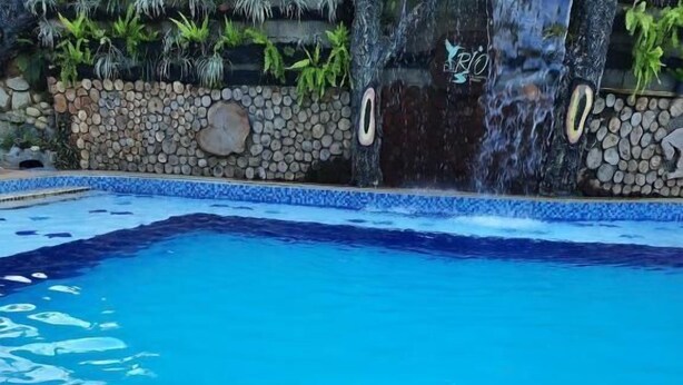 A poolside setting with a wooden table holding fruits, a glass of drink, and a potted plant. - Finca hotel Sendero del rio (San Rafael)