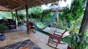 An outdoor patio area with tiled flooring, wooden furniture, and potted plants. - Finca hotel Sendero del rio (San Rafael)