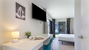 A hotel room with a bed, a desk with a lamp, a TV, and a window with curtains. - Laian Branded Residensed House with Private Pool and Air Conditioning (Triquivijate)