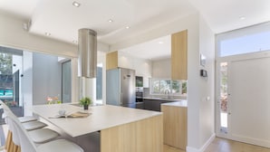 A modern kitchen with a central island, stainless steel appliances, and a view to the outside. - Laian Branded Residensed House with Private Pool and Air Conditioning (Triquivijate)