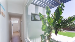 A modern interior with a wooden floor, a view of a garden, and a large window with a view of the outdoors. - Laian Branded Residensed House with Private Pool and Air Conditioning (Triquivijate)