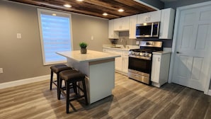 A modern kitchen with a central island, stainless steel appliances, and a wooden ceiling. - Lux Utica Retreat  (Utica)
