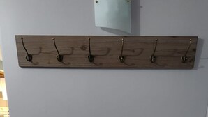 A bench with a light-colored cushion against a grey wall, a wooden shelf with hooks, and a cylindrical light fixture above. - Lux Utica Retreat  (Utica)