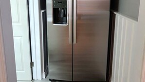 A compact kitchen with a stainless steel refrigerator, a built-in water dispenser, and a wooden floor. - Lux Utica Retreat  (Utica)