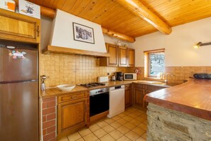 Une cuisine avec des meubles de rangement en bois, un réfrigérateur, une cuisinière, un lave-vaisselle et un four à micro-ondes.