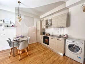 A modern kitchen with wooden cabinets, a built-in oven, a dishwasher, and a washing machine.