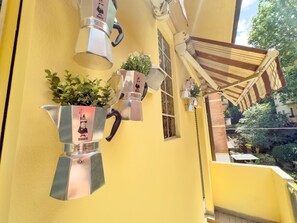 A yellow building with a metal structure on the wall, a small window, and a wooden awning. - BeHappyS[Charming Balcony]-Near the centre&Rizzoli (Bologna)