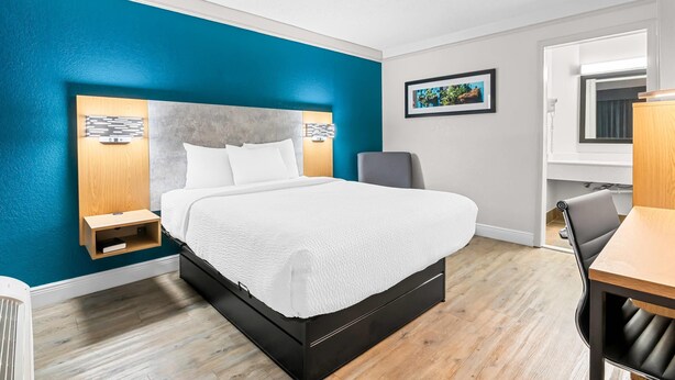 A hotel room with a bed, a desk, and a chair.
