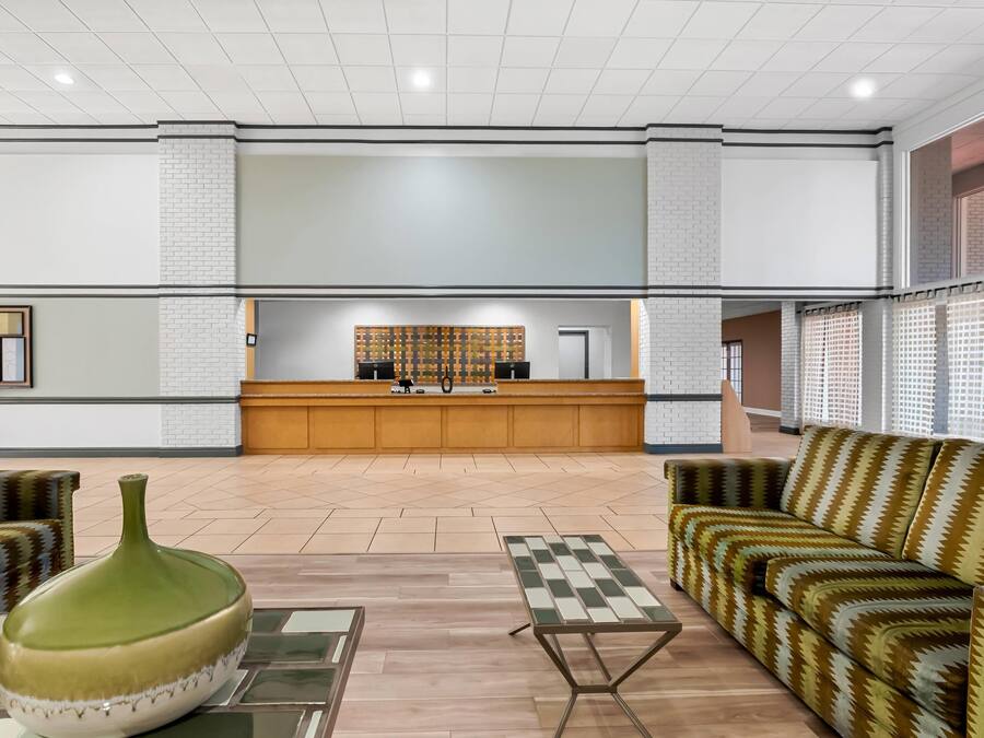 Un hall amplio con un mostrador de recepción, sofás estampados, un jarrón verde y una mesa de ajedrez.