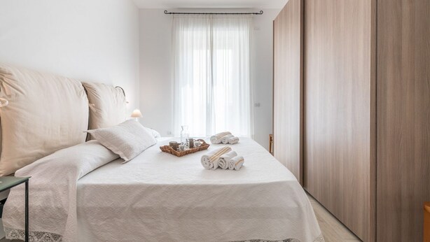Un lit bien fait, avec des oreillers, une table de chevet avec une lampe et un plateau contenant des serviettes et un verre.