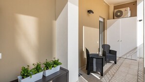 Un appartement moderne doté d’un balcon, d’un coin repas avec des meubles en osier et d’un réfrigérateur blanc.