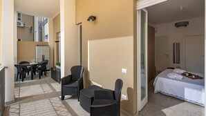 Une chambre d’hôtel comprenant un lit, une petite table avec des chaises et un balcon aménagé avec une table et des chaises.