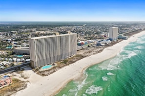 A coastal hotel with a beach view, multiple floors, and a swimming pool.