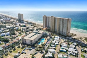 A coastal hotel with multiple high-rise buildings, a swimming pool, and a beach view.
