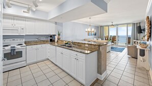 A modern kitchen with white cabinets, granite countertops, and a large island. - 2bd 2ba, Sleeps 8, Seasonal Beach Service (Panama City Beach)