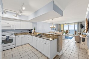 A modern kitchen with white cabinets, granite countertops, and a large island.