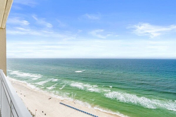 A beach view from a balcony with a clear sky.