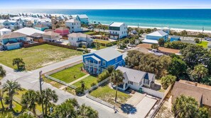 A coastal residential area with houses, a beach, and a clear sky.