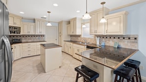 A modern kitchen with beige cabinetry, a central island, and pendant lighting. - Sleeps 14, Game Room, Gated Beach Access, Pet Friendly (Panama City Beach)