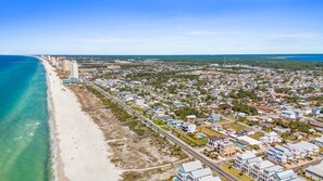 An aerial view of a coastal town with a beach, residential areas, and a mix of commercial buildings.