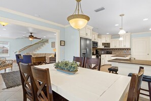 Une cuisine spacieuse avec des meubles blancs, un îlot central et un coin repas comprenant des chaises et une table en bois.