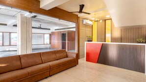 A modern reception area with a sofa, a reception desk, and a view of the outside.
