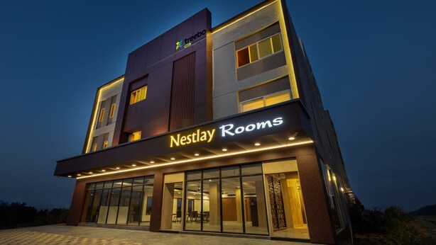 A modern hotel building with a sign reading "Nestlay Rooms."