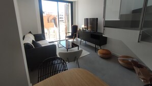 Ein modernes Wohnzimmer mit Sofa, Fernseher und Essbereich.