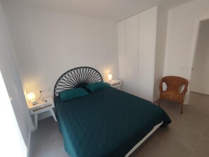 Cozy retreat with a single bed, two bedside tables, and a wicker chair.
