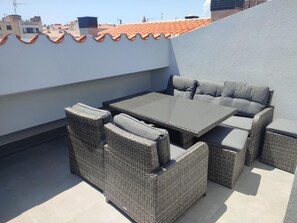 Relax on the rooftop with a set of wicker furniture, including a table, chairs, and bench.