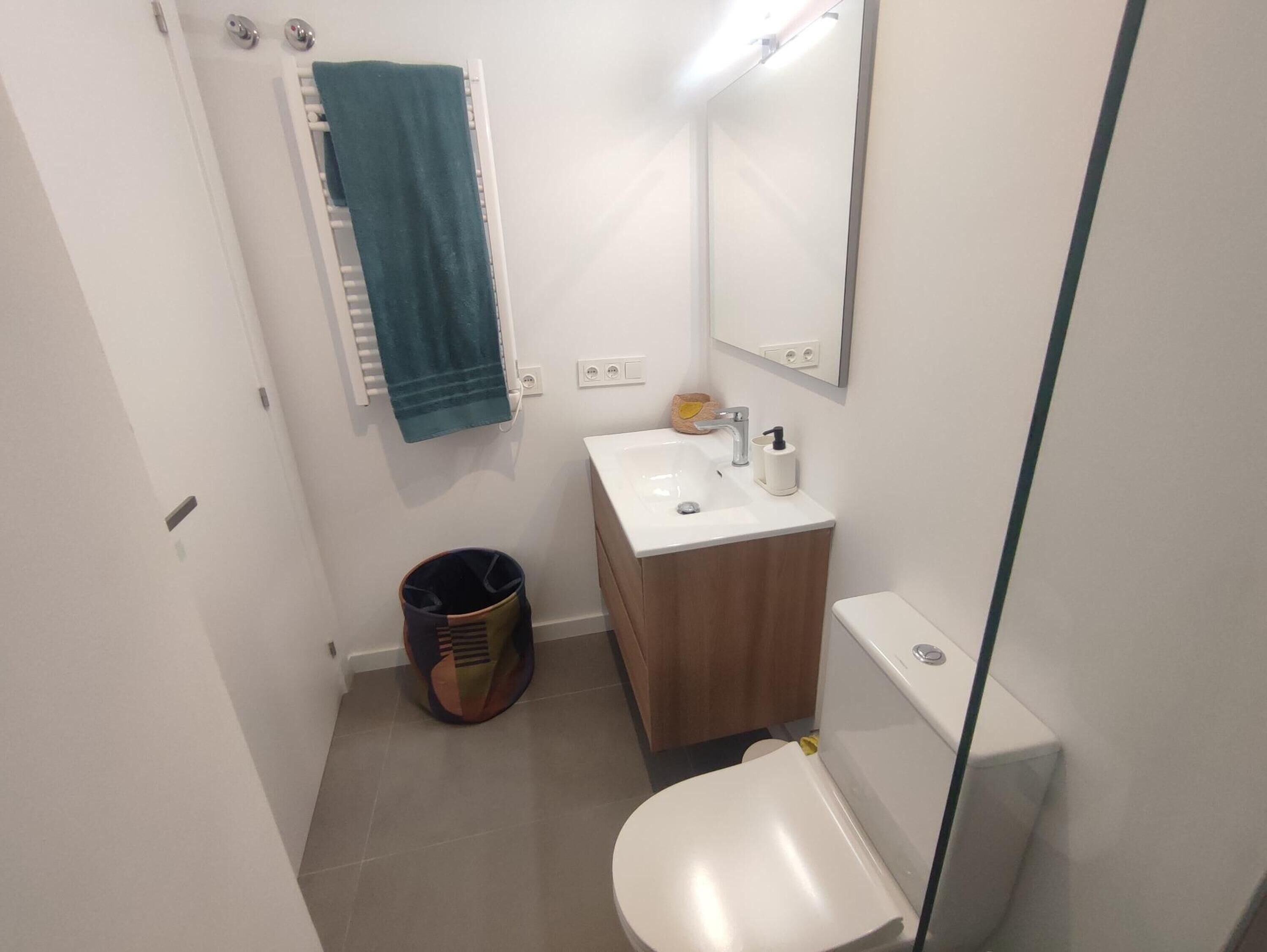 Une petite salle de bain avec un lavabo blanc, un miroir et des toilettes.