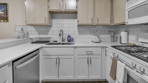 A modern kitchen with white cabinets, a stainless steel stove, and a microwave. - Central Downtown Living (Buffalo)